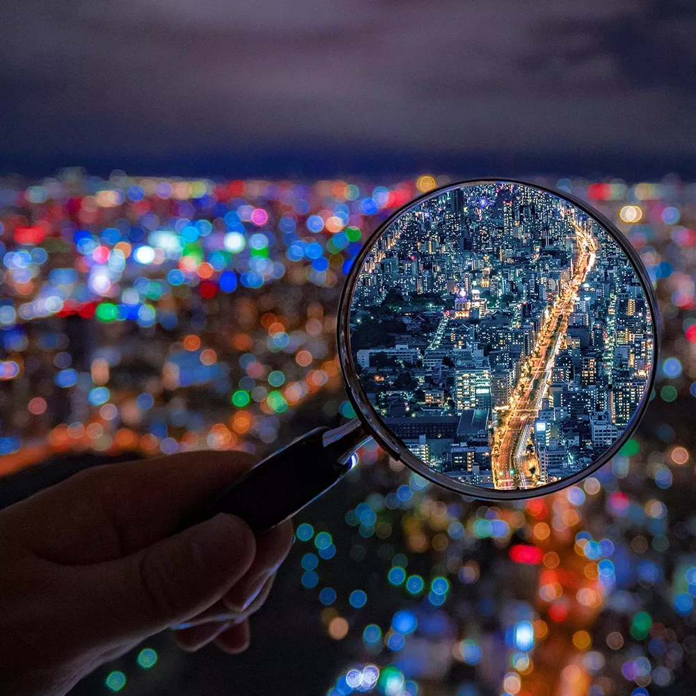 Magnifying glass highlighting a city street at night, symbolizing investigation, transparency, and complaint review processes.
