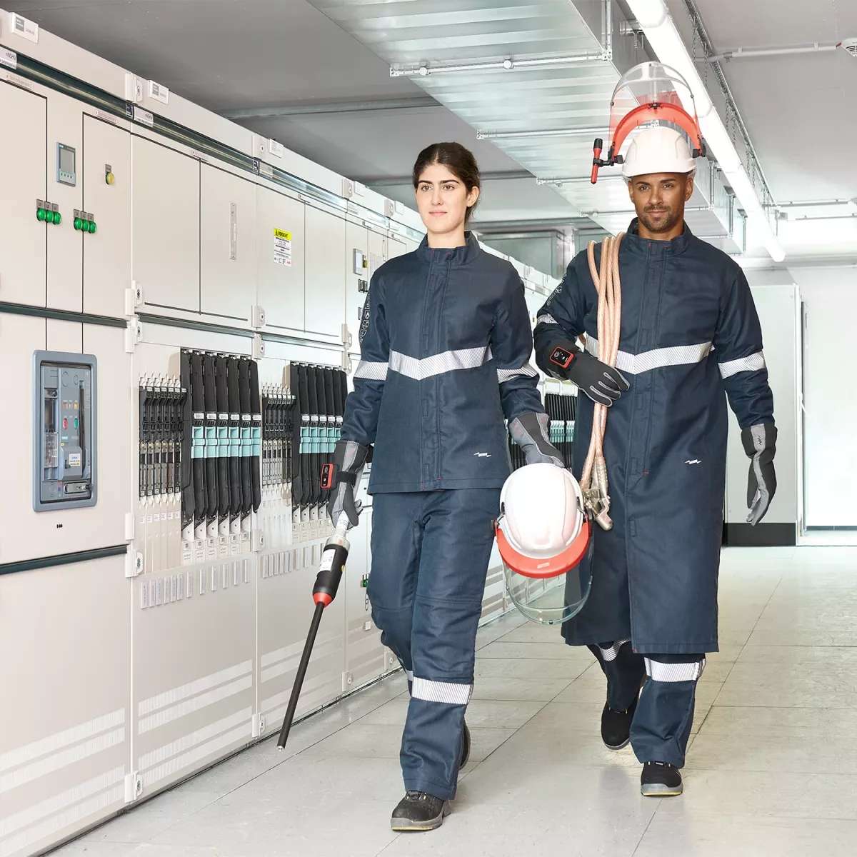 A man and a woman walk through a factory hall, surrounded by machines and production equipment.
